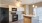 well lit kitchen area with sink in the island and wine rack above fridge